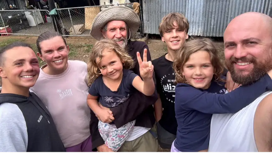 A young girl wearing a dark blue t-shirt with a white star design and floral-patterned shorts.