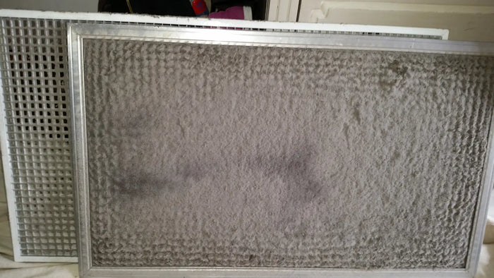 Dirty gray air filter with a metallic frame.